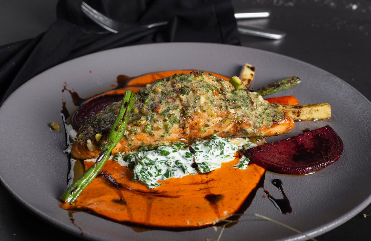 A beautifully plated salmon dish with vibrant vegetables and sauce, perfect for a gourmet dining experience.