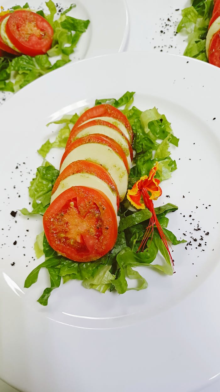 Delicious fresh Caprese salad with tomatoes, mozzarella, and edible flowers on a bed of lettuce.